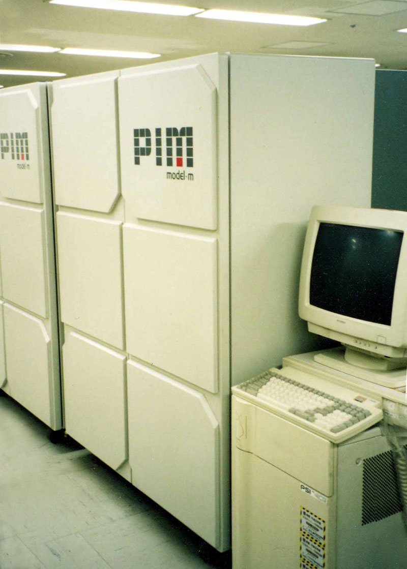 Two large computer towers that read "PIM model-m," next to a boxy computer monitor like you would see in the 1990s.